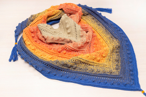 knitted bactus scarf, on a light background. Textured yarn scarf with color gradient.