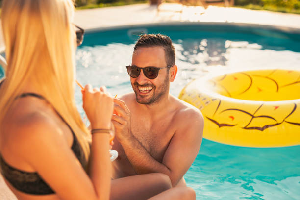 istock Couple drinking cocktails by the swimming pool 1198097672