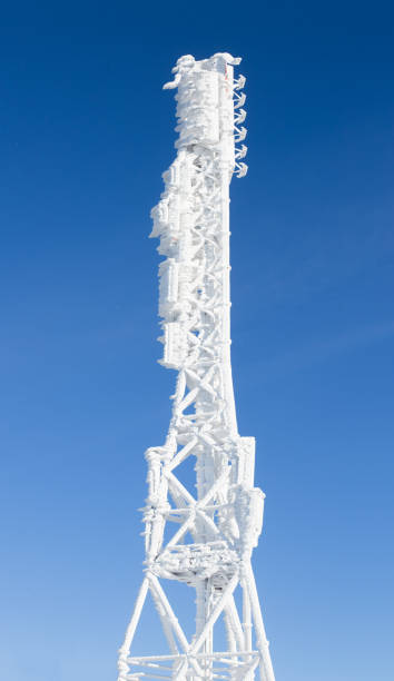 Icy cellular base station antenna covered with snow. Cell site tower on moutain hill.