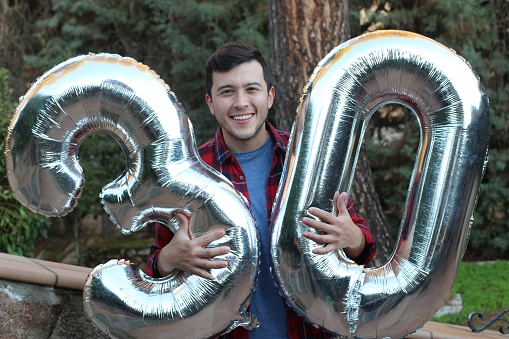 Man turning 30 holding inflatable balloons.