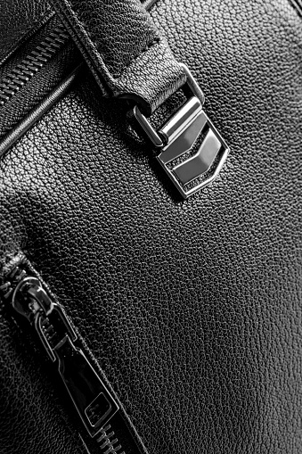 Close-up of a black briefcase (faux leather texture). Space for copy.