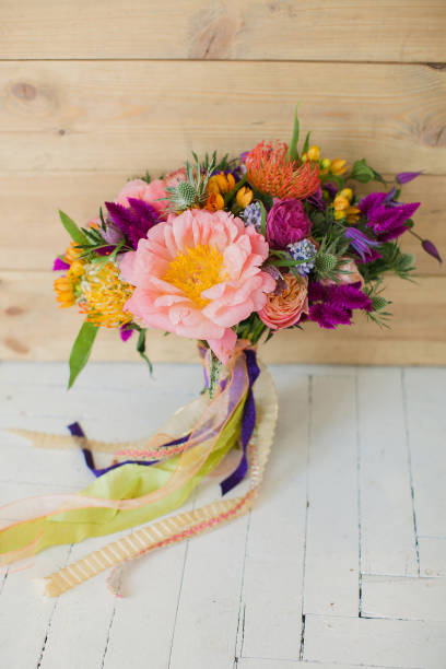 istock Workshop on creating bouquets and flower arrangements in the style of boho chic. Wedding celebration flowers for the bride. Pink peonies, red roses. White floor on a wooden background. 1198123721