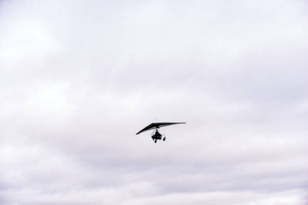 person flying away into the horizon on a small aircraft single seat microlight as a hobby or sport in the air - extreme sports air sport recreational pursuit ultralight imagens e fotografias de stock