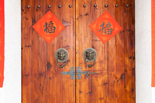Two Handwriting Chinese blessing Fu on the  traditional chinese  wooden door with brass handle. The Fu with red background or writing red, luck and happiness in Chinese connotation