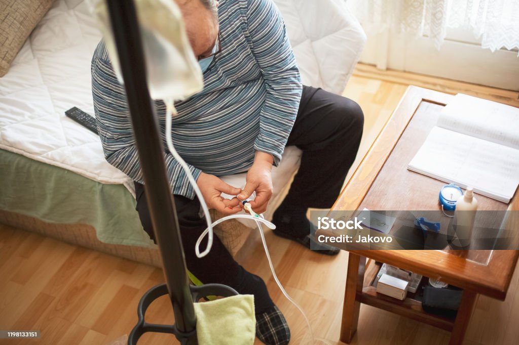 Senior man connecting peritoneal dialysis with catheter at home Dialysis Stock Photo