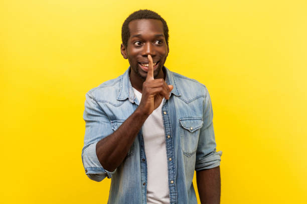 istock Please, keep silence. Portrait of cheerful handsome man gesturing to be quiet. indoor studio shot isolated on yellow background 1198137112