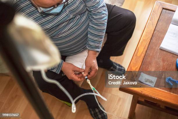 Senior Man Connecting Peritoneal Dialysis With Catheter At Home Stock Photo - Download Image Now