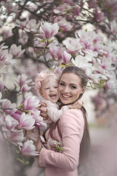 piękna i szczęśliwa mama z córką w kwitnącej magnolii. - sweet magnolia tree blossom white zdjęcia i obrazy z banku zdjęć