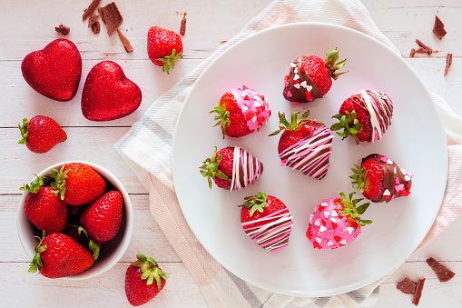 Valentines Day chocolate dipped strawberries. Above view table scene over a white wood background. Love and heart theme.