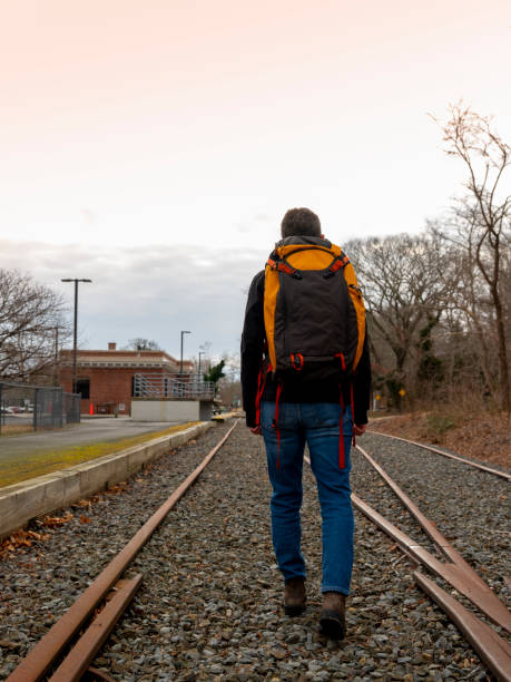 istock Person wearing a backpack walking along railroad tracks 1198143132