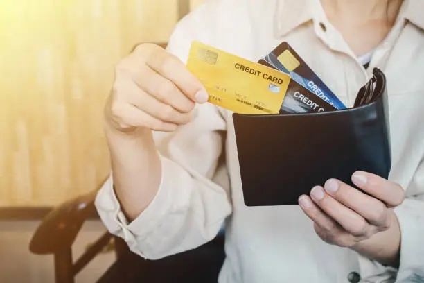 Photo of Cropped shot view of female hands picking credit cards from her wallet.