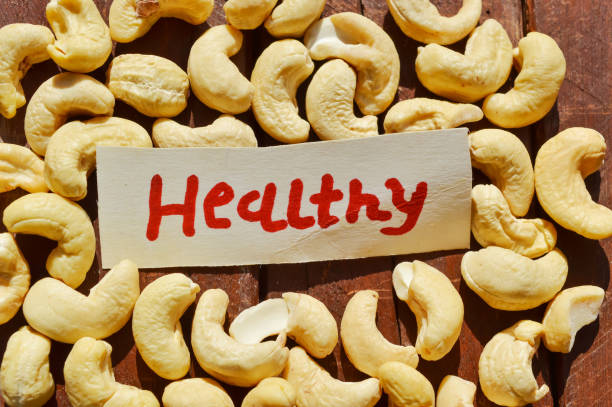 カシューナッツクローズアップビュー、カシューナッツと木製のテーブル上の健康的な書き込み、健康なナッツ、黄色の健康なナッツ - cashew close up food salted ストックフォトと画像