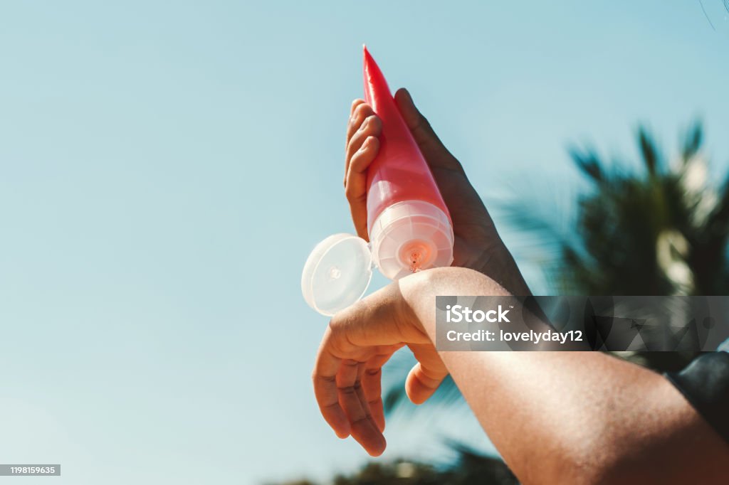 Nahaufnahme junge Frau Anwendung Sonnencreme Lotion auf der Hand mit blauen Himmel Hintergrund - Lizenzfrei Sonnencreme Stock-Foto