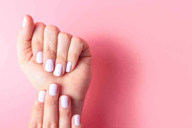 istock Female hands with white manicure on pink background with copy space 1198160647