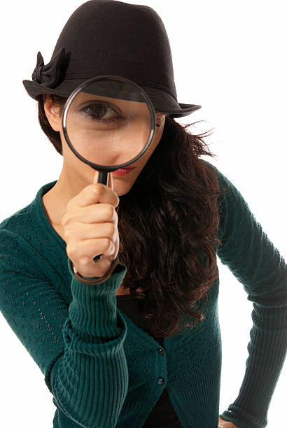 Young woman looking through magnifying glass loupe detective isolated stock photo