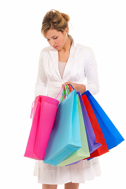 Young woman with shopping bags standing looking into bag isolated stock photo