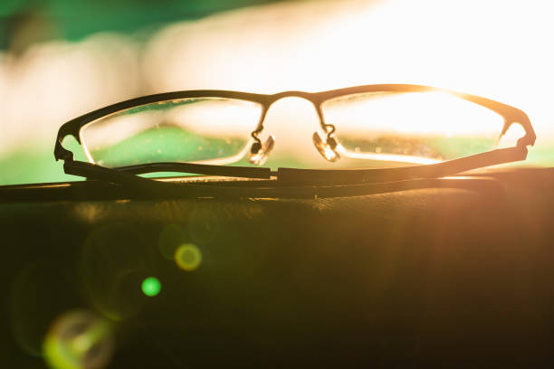 Close-up glasses with camera flare at sunrise blurred background
