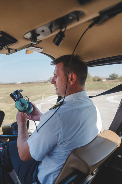 istock Helicopter pilot sitting in cockpit with headphones in hands 1198179427