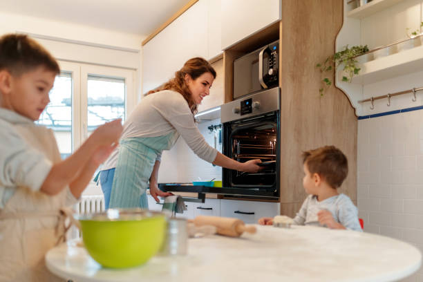istock Mother putting baking tray into oven 1198191033