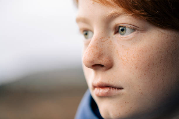 Close-up of boy looking away. Male child is having freckles on face. He is contemplating.