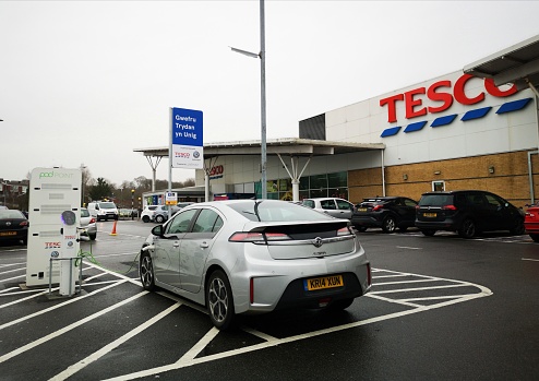 Neath, UK: January 07, 2020: A car is recharging it's electric batteries at a charging station in a Tesco car park. Pod Point is a leading UK provider of charging infrastructure for electric vehicles and is sponsered by Volkswagen.