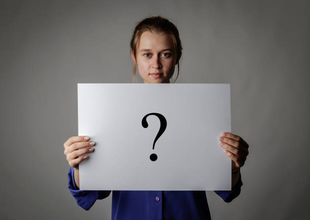 istock Young woman in blue is holding white paper. Question Mark. 1198196140