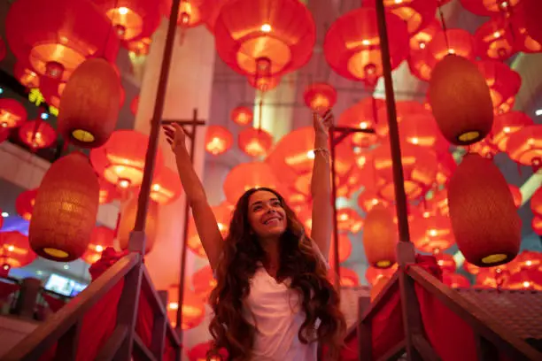 Photo of Happy tourist woman enjoying traditional red lanterns decorated for Chinese new year Chunjie. Cultural asian festival in Beijing.