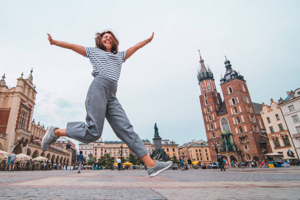 背景にクラクフ市場広場聖マリア教会でジャンプ市観光コンセプト女性 - krakow people poland church ストックフォトと画像