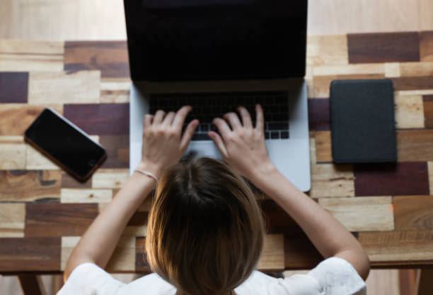 istock Woman's hands typing on laptop keyboard top view. Study and work online, freelance. Self employed or freelance woman, girl working with her laptop sitting at wooden table with a phone and ereader. 1198200273
