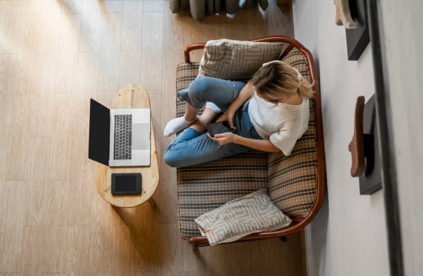 istock Woman use a smartphone while lying on a sofa with a laptop and ereader on a table. Studying online, freelance. Self employed or freelance girl use a phone and resting from work whith a notebook. 1198200341