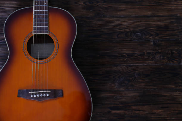 istock Six string folk acoustic guitiar over aged wood background. 1198202461