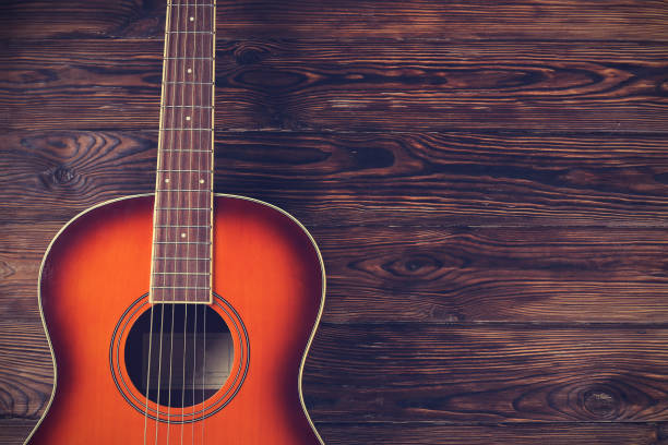 istock Six string folk acoustic guitiar over aged wood background. 1198202487
