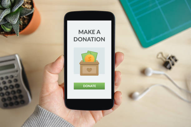 Make a donation concept Hand holding smart phone with donate concept on screen. Top view charitable donation stock pictures, royalty-free photos & images