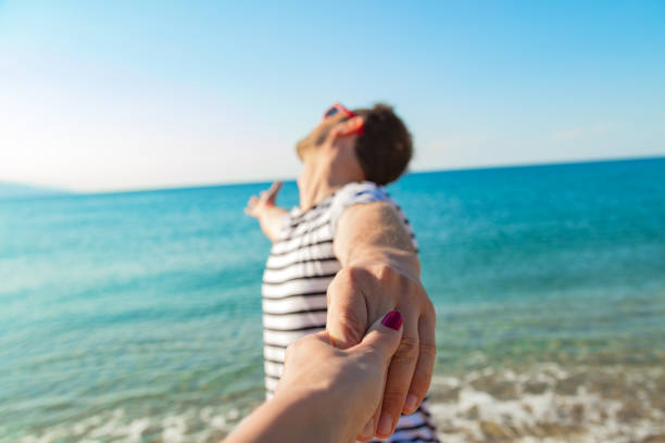 Girlfriend and boyfriend holding hands on a sandy tropical beach.