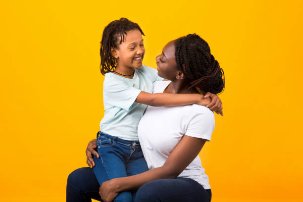 glückliche afrikanische amerikanische familie isoliert über gelbem hintergrund - auf dem schoß stock-fotos und bilder