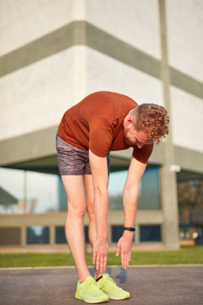 istock Young man exercising / stretching in urban park. 1198216532