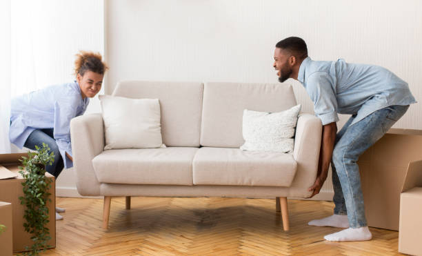 istock Couple Lifting Sofa Standing In Empty Room After Moving House 1198216682