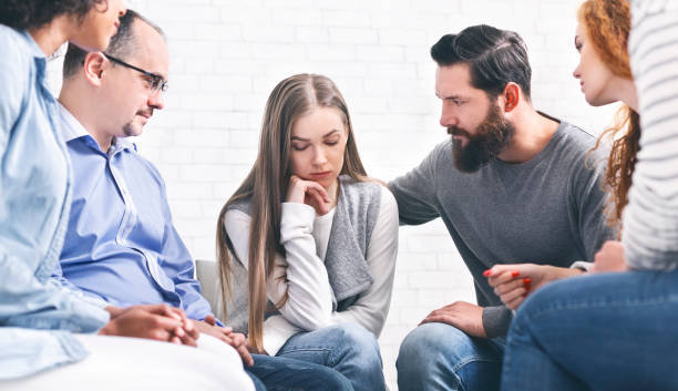 istock Patients comforting depressed woman at therapy session 1198216833