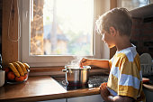 Little boy stirring soup in the pot