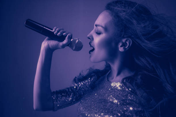 istock Caucasian female singer portrait isolated on purple studio background in neon light 1198217841