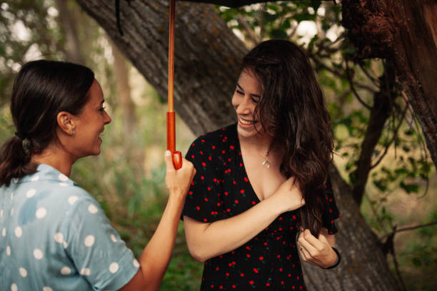 istock Two young women standing with umbrella on field 1198218646