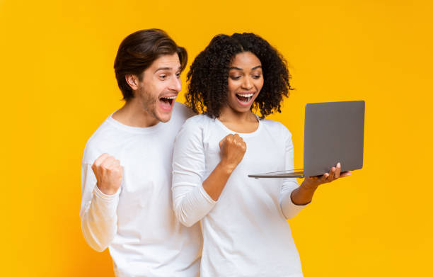 istock Joyful interracial couple celebrating win with laptop 1198218798