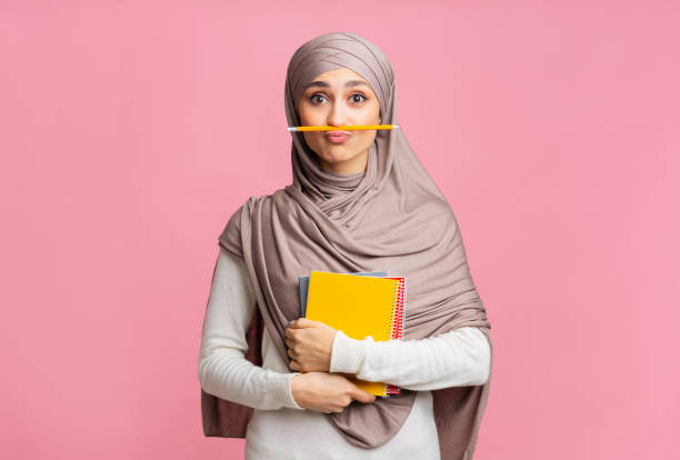 studentessa musulmana in hijab con matita come baffi e quaderni - nerd computer learning fun foto e immagini stock