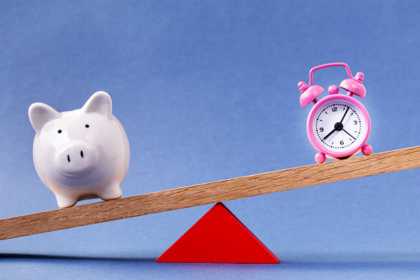 istock Alarm clock and piggy bank balancing 1198219020