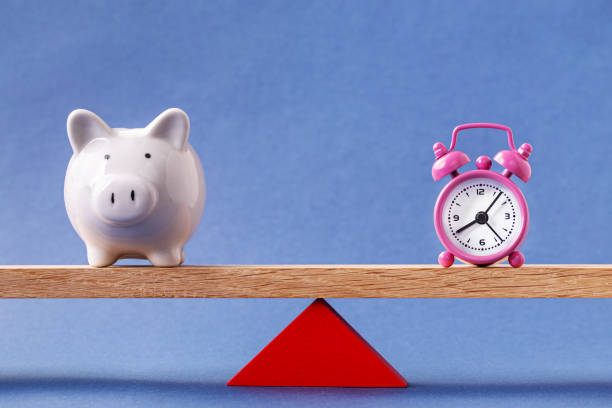 istock Balanced alarm clock and piggy bank 1198219033