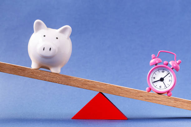 istock Balancing piggy bank and alarm clock 1198219038