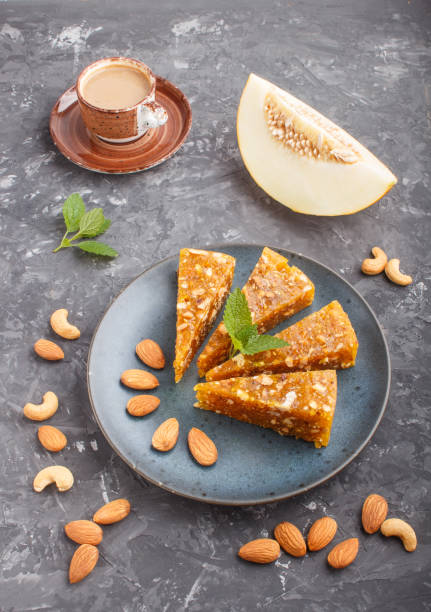 istock Traditional turkish candy cezerye made from caramelised melon, roasted walnuts, hazelnuts, cashew, pistachios in blue ceramic plate and a cup of coffee on a black concrete background. side view, close up. 1198219071