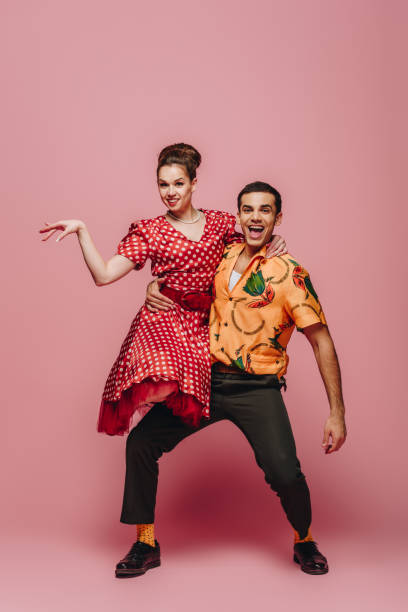 stylish dancer holding woman while dancing boogie-woogie on pink background stylish dancer holding woman while dancing boogie-woogie on pink background boogie woogie dancing stock pictures, royalty-free photos & images