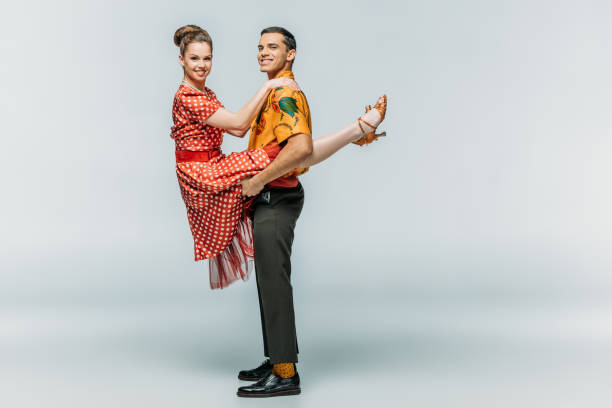 istock cheerful man holding woman while dancing boogie-woogie on grey background 1198219931
