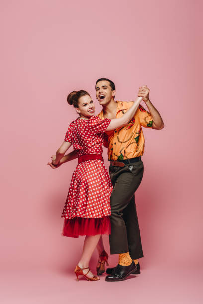 istock stylish dancers holding hands while dancing boogie-woogie on pink background 1198219932